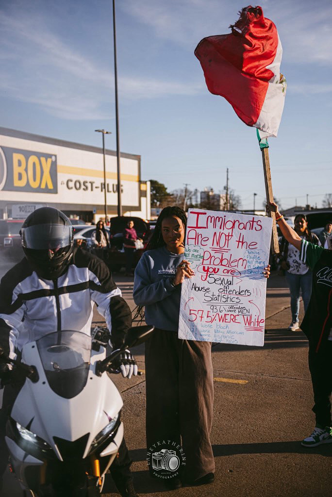 Faith Scott, 11, participates in a protest against the new immigration order outside of the Ten Box store. Photo | Laney Katherine